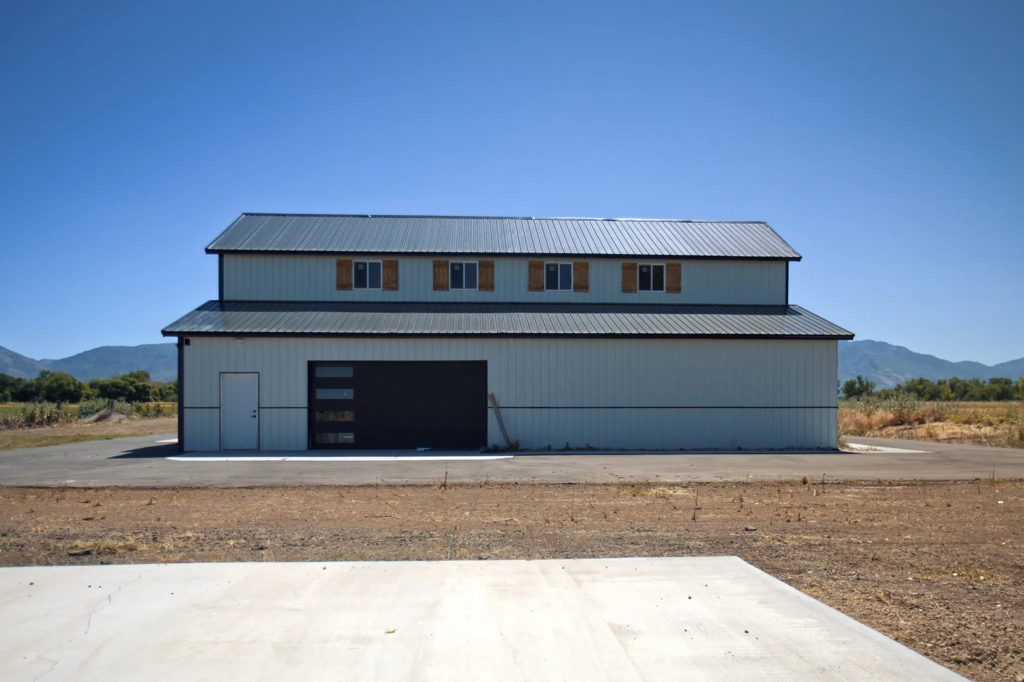 Two-story structure featuring a metal roof and light-colored vertical siding