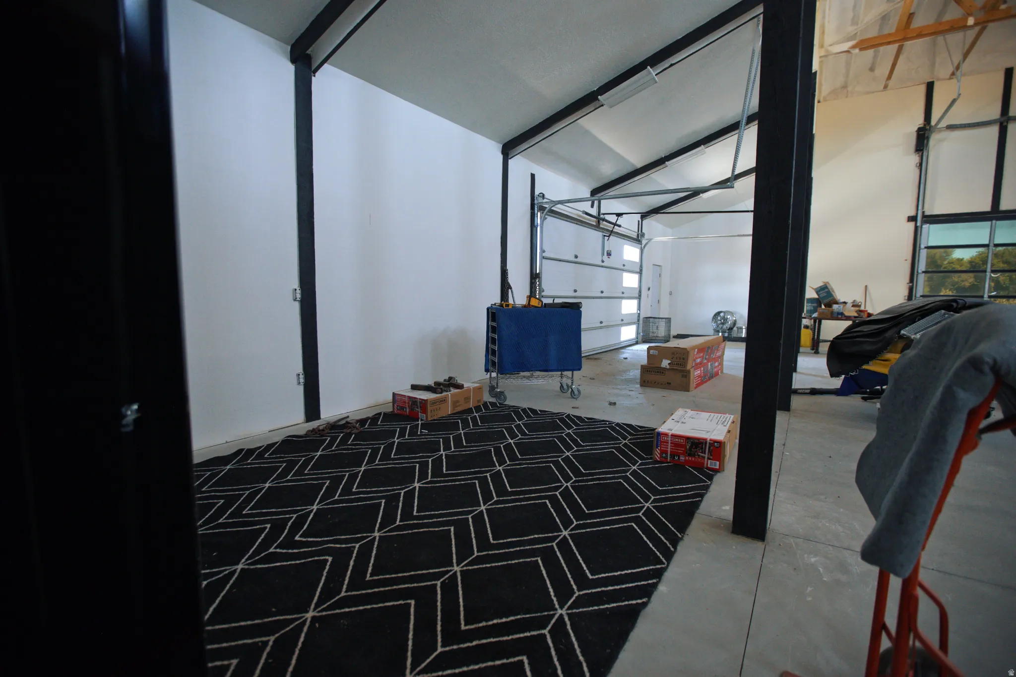 Spacious interior featuring a concrete floor, white walls, and exposed black structural beams