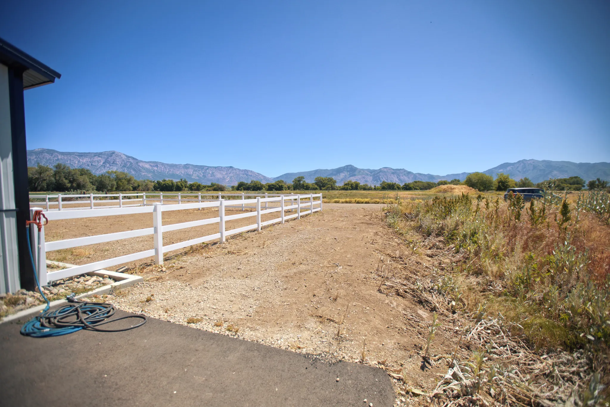 Expansive outdoor area featuring a white vinyl fence enclosing a large, open field