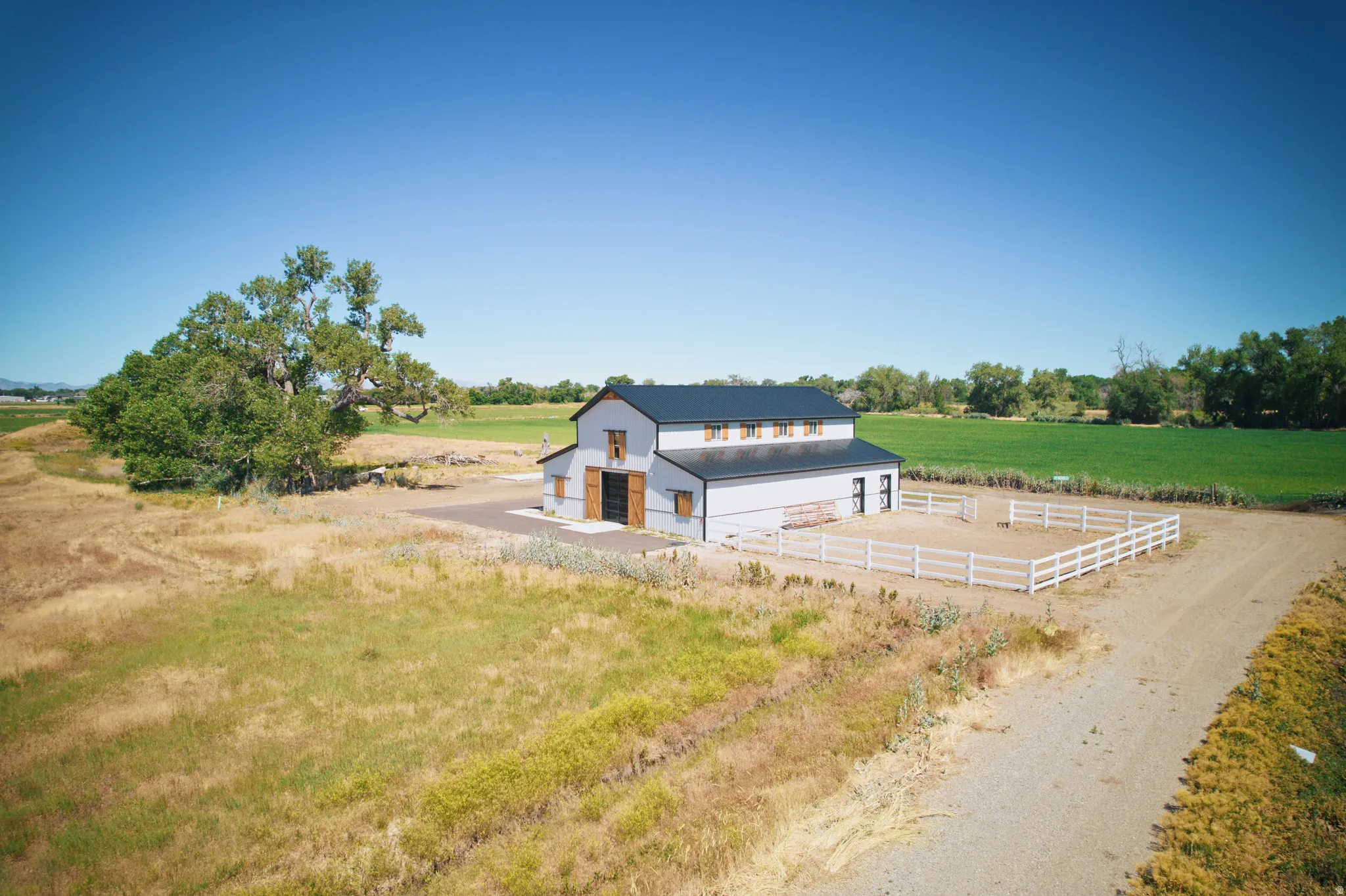 Modern barn structure featuring a dark roof, light gray siding, and natural wood barn doors