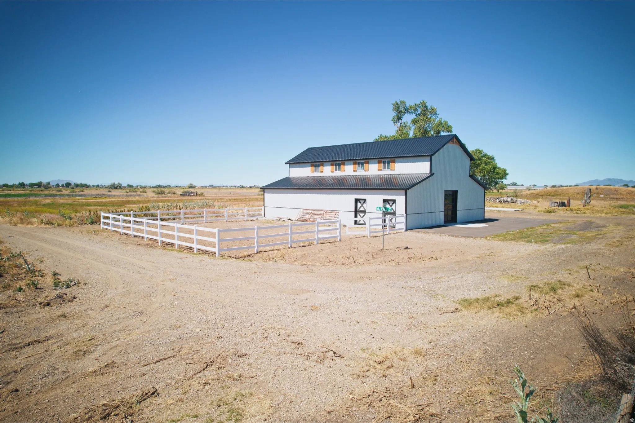 Two-story barn structure featuring white siding, a dark roof, and wood-finish shutters