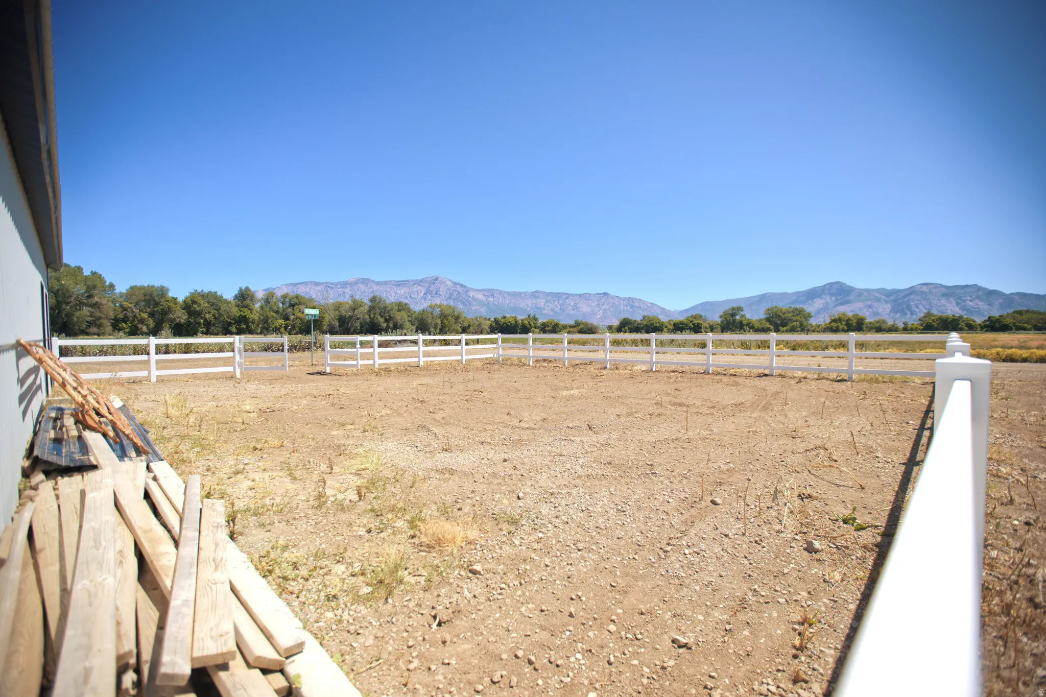 Expansive outdoor space featuring a white post-and-rail fence