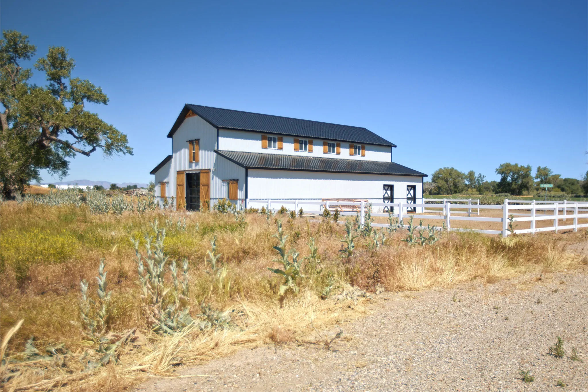 Two-story structure featuring white siding, a dark roof, and multiple brown-toned window shutters