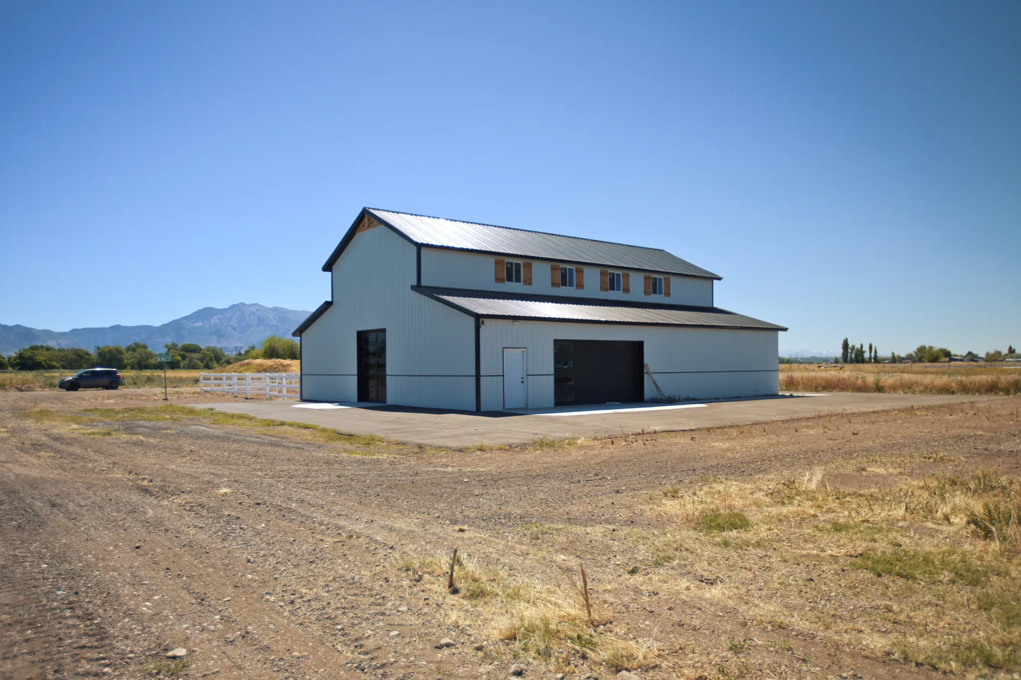 Two-story pole barn structure with a metal roof and light-colored siding