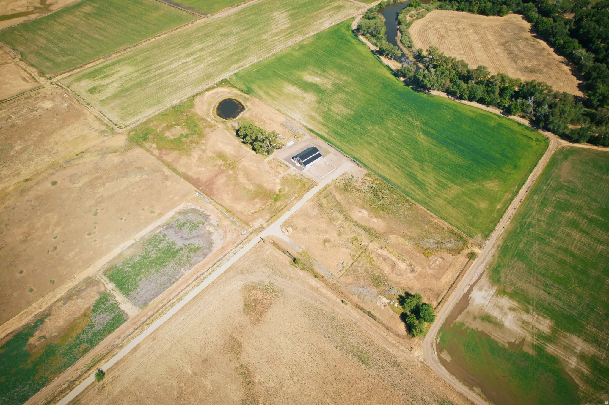 Expansive rural property featuring varied agricultural fields and a winding creek