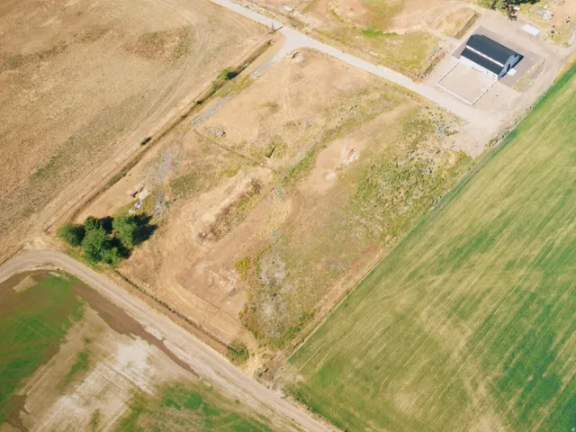 Expansive agricultural landscape featuring varied terrain, a large dark-roofed structure, and multiple water features including a pond and a river
