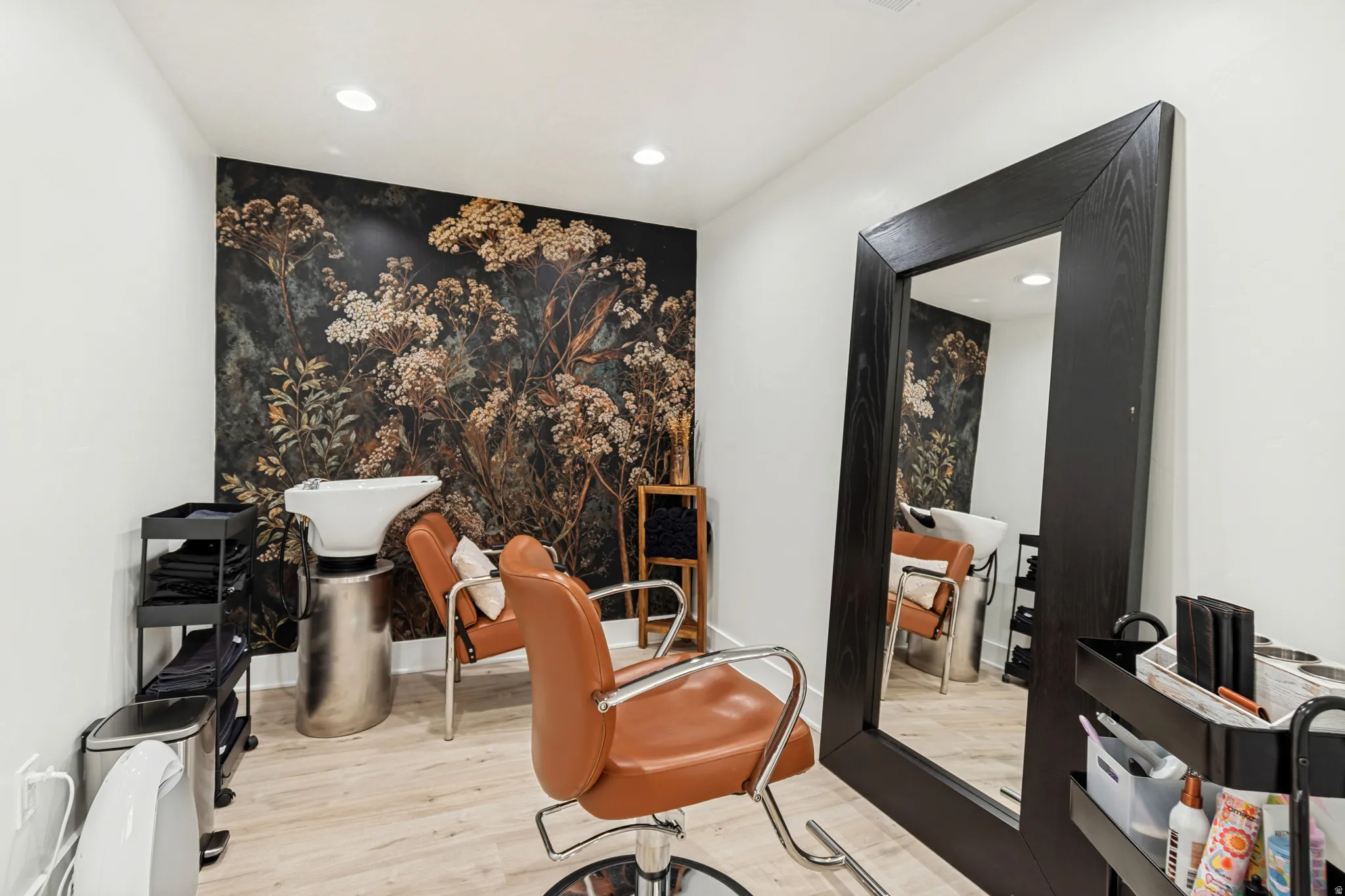 Specialty room featuring a botanical accent wall, wood-finish flooring, recessed lighting, and a large framed mirror