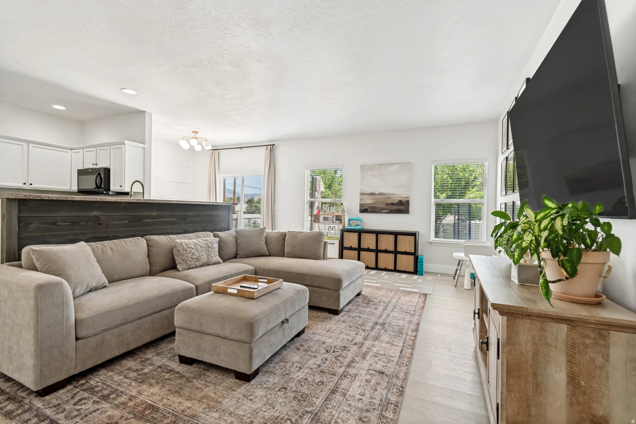 Open-concept living space featuring light wood-finish flooring, white walls, and recessed lighting