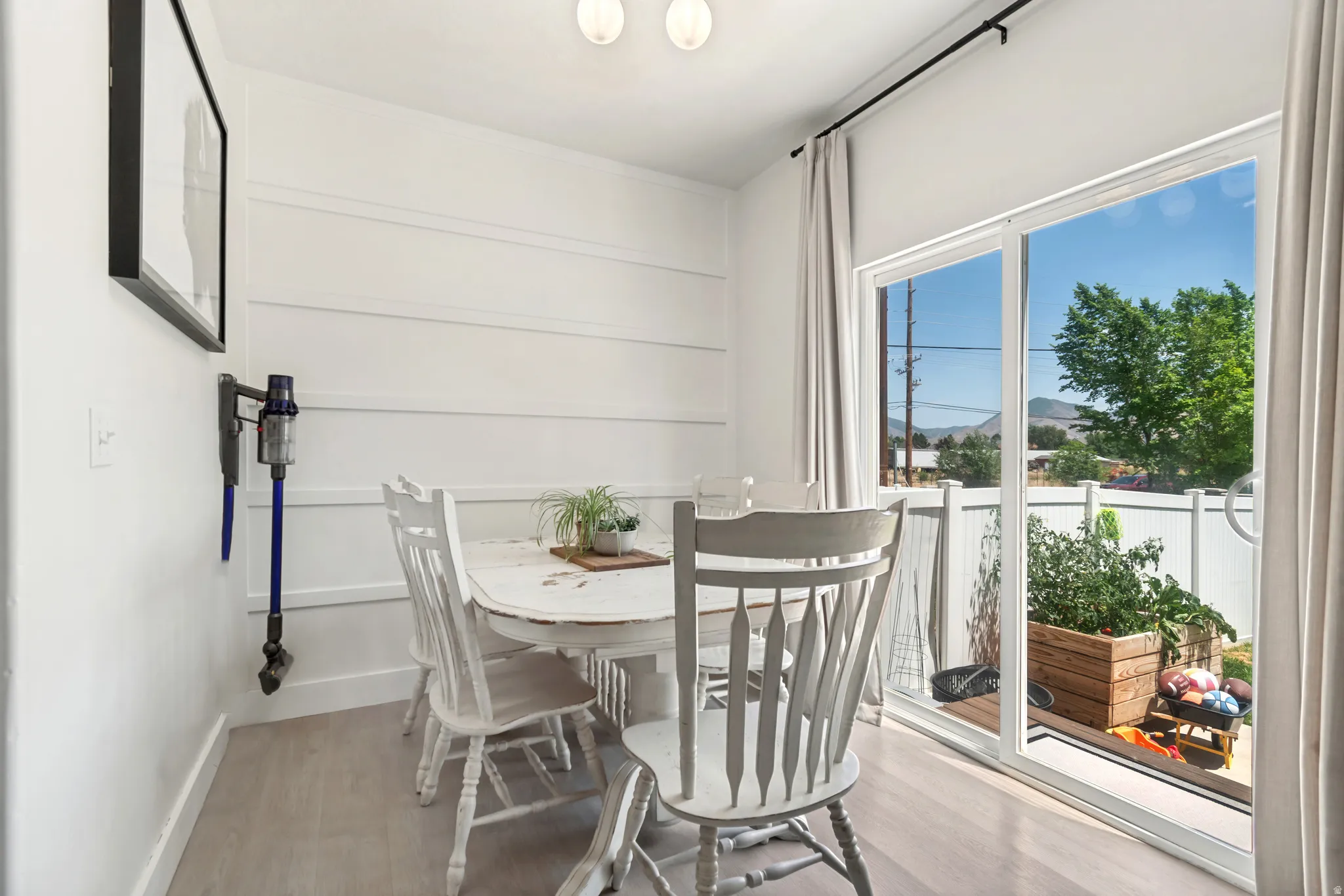 Dining area with light wood-finish flooring, white shiplap accent wall, and ceiling-mounted light fixtures