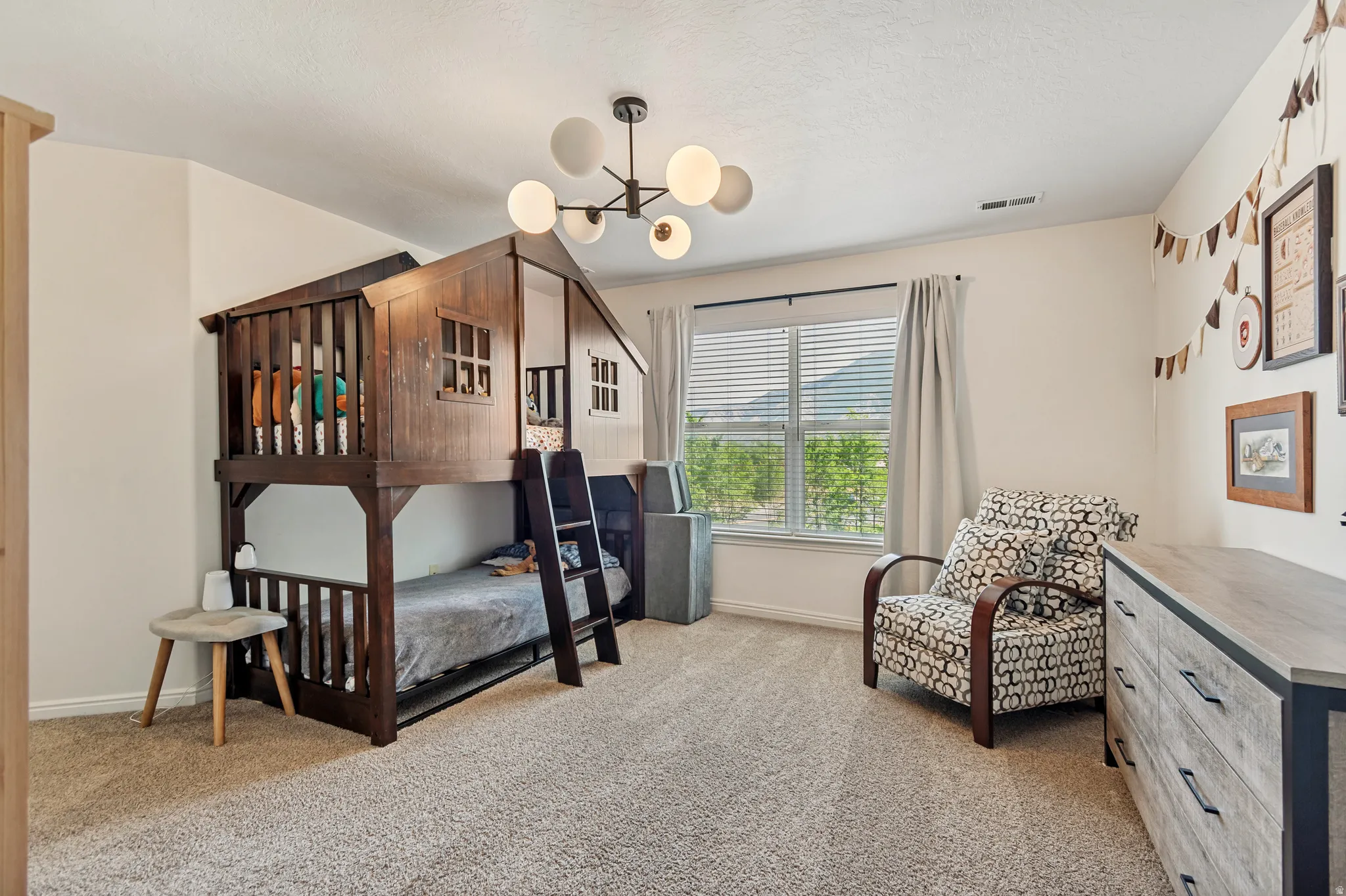 Windowed room with textured carpeting, a modern ceiling light fixture, and neutral wall tones