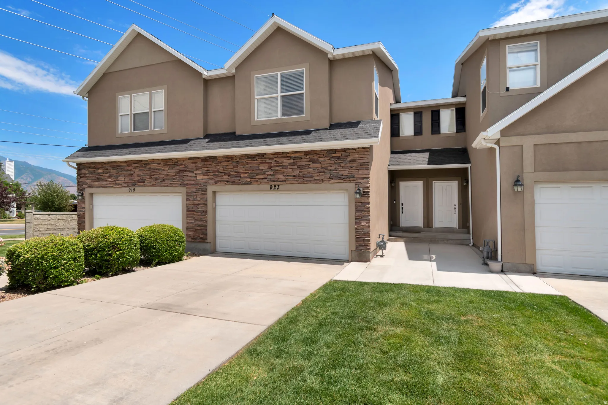 Multi-unit residence featuring stucco and stone veneer facade, integrated two-car garages, and individual entry doors