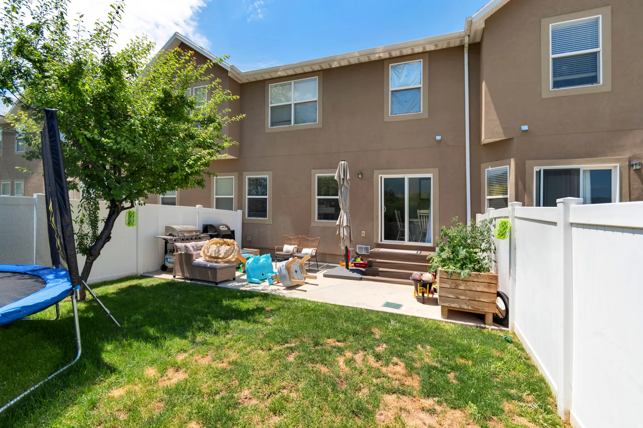 Fenced backyard featuring a manicured lawn, a concrete patio, and a mature shade tree