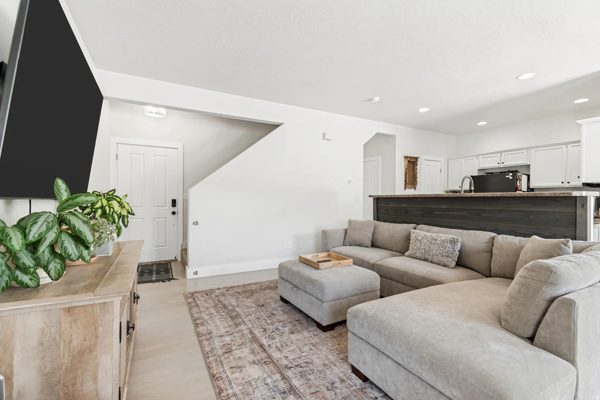 Open concept living space featuring light wood-finish flooring, recessed lighting, and a white paneled entry door