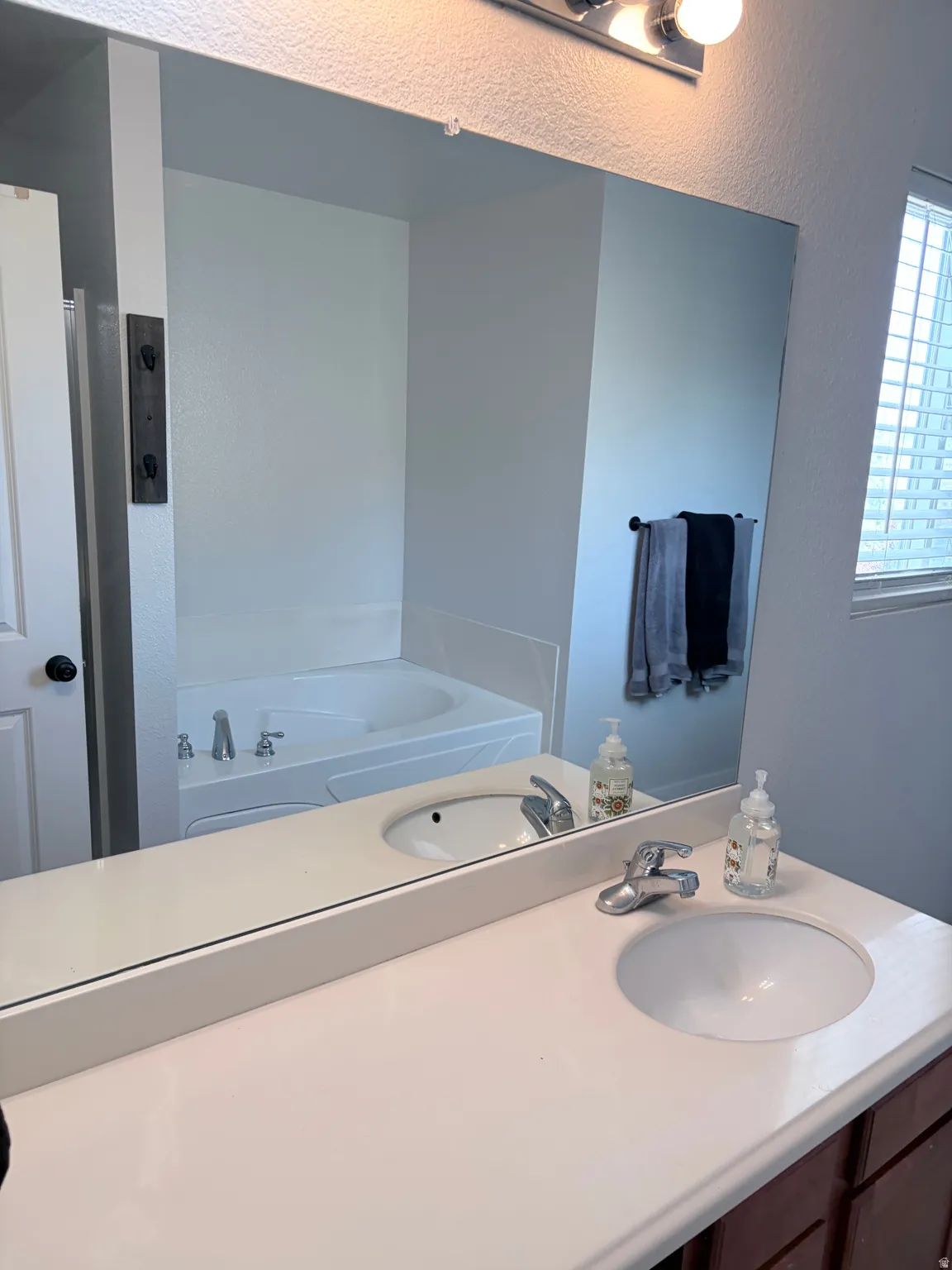 Bathroom vanity featuring a light-toned countertop with integrated dual sinks and chrome fixtures