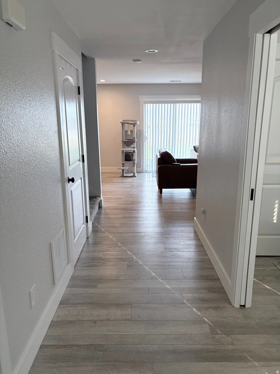 Hallway with wood-finish flooring, white baseboards, and a white paneled door