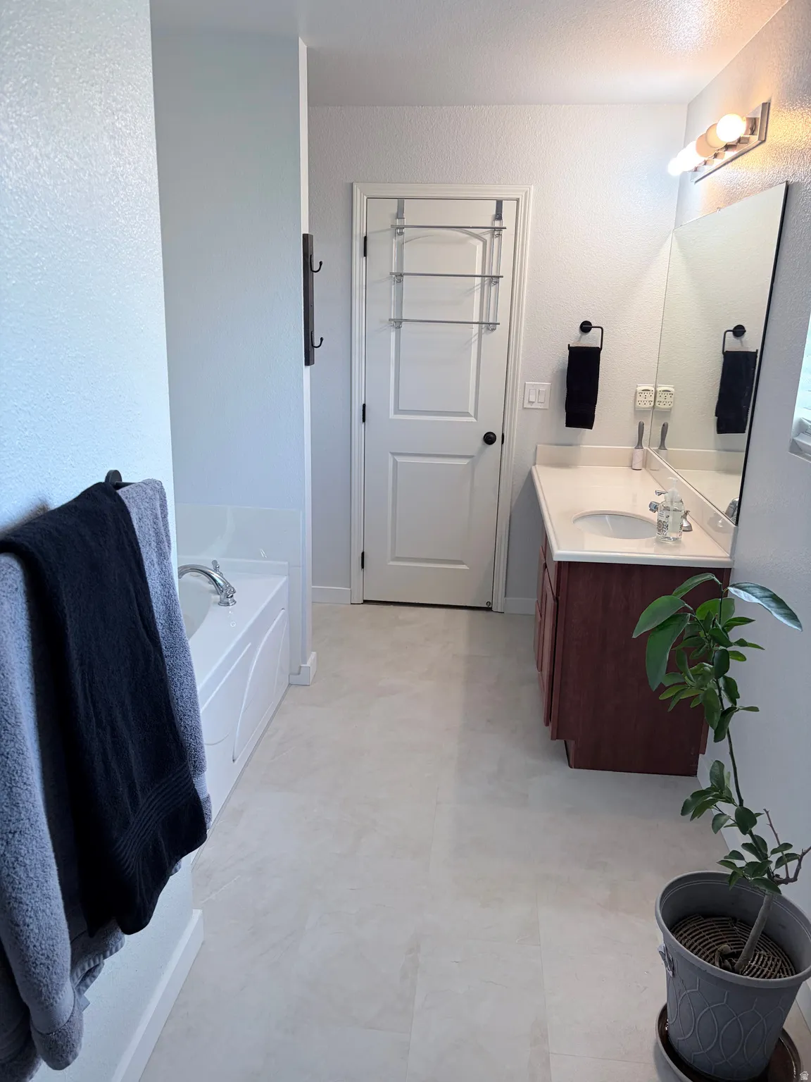 Bathroom featuring a built-in tub, a single vanity with a white countertop, and tile flooring