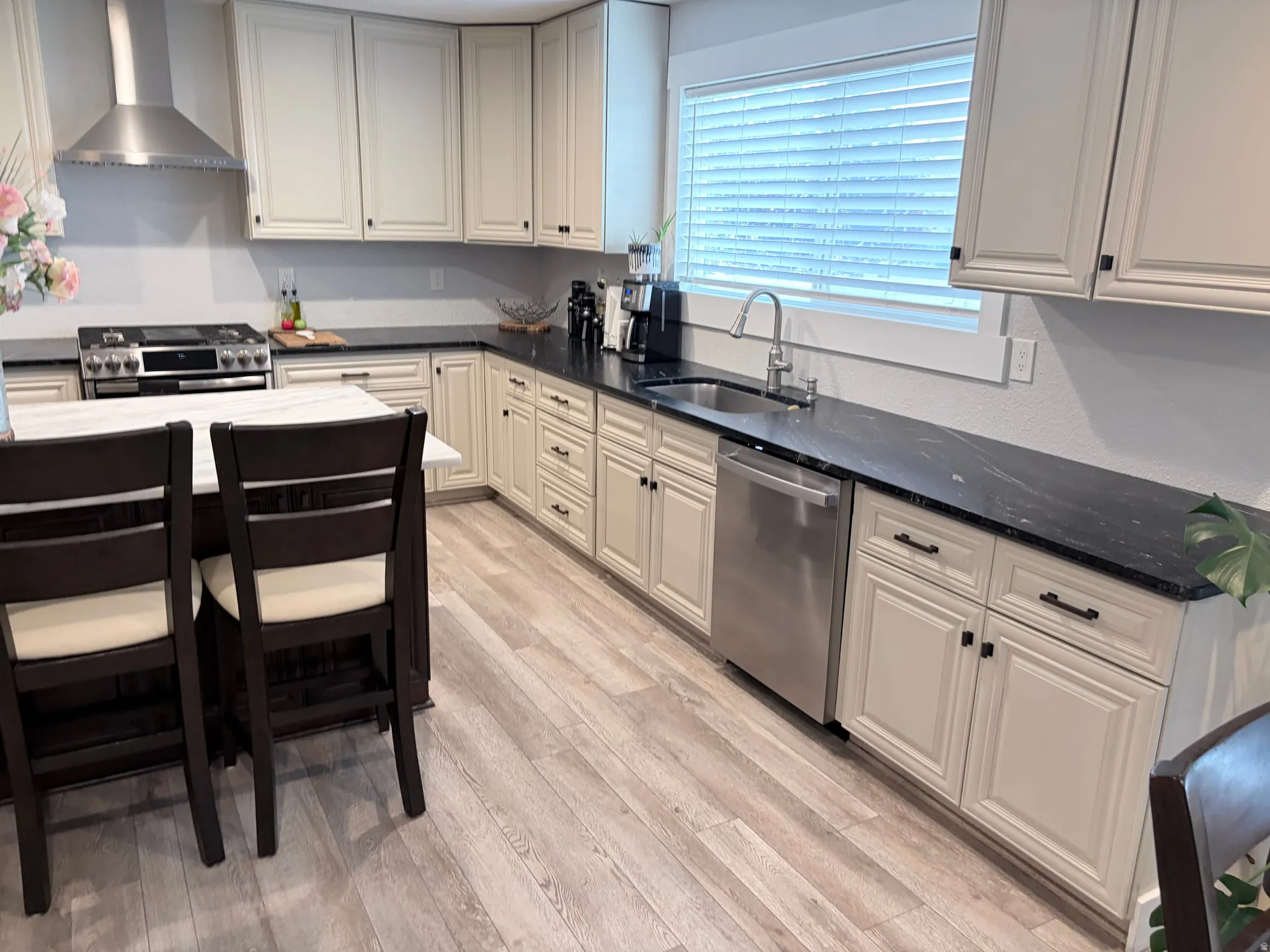 Kitchen featuring light-toned cabinetry, dark countertops, and wood-finish flooring