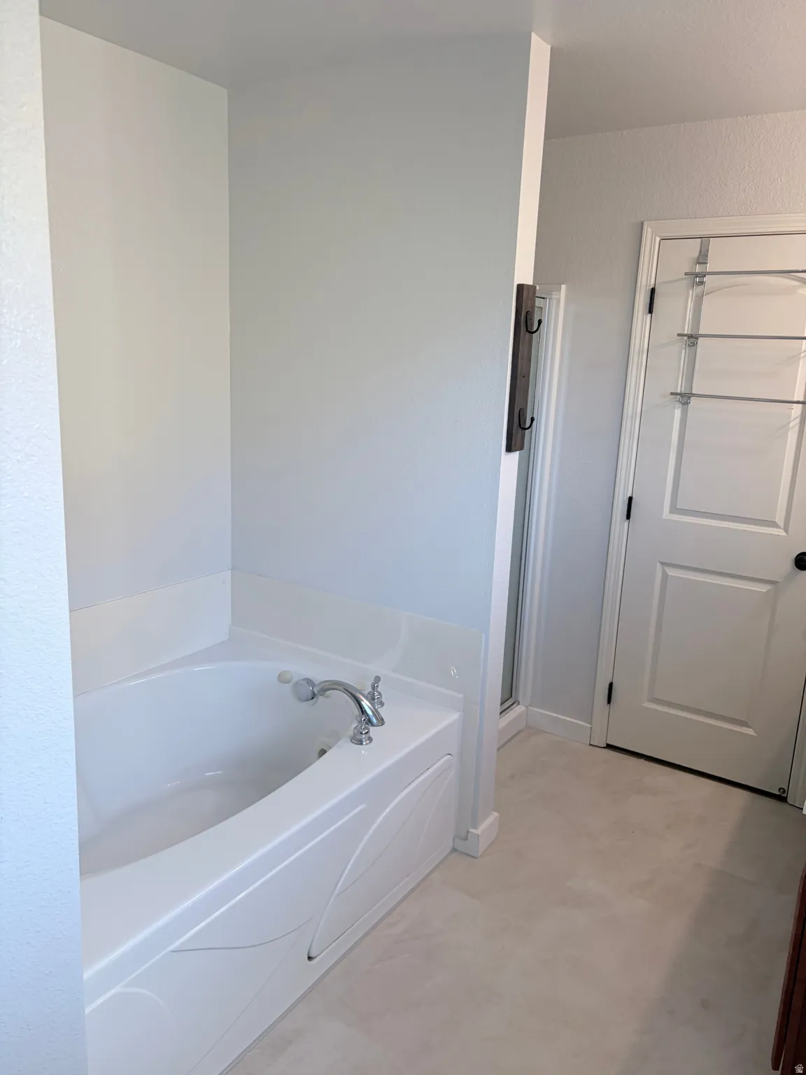 Soaking tub with chrome fixtures and light-toned flooring