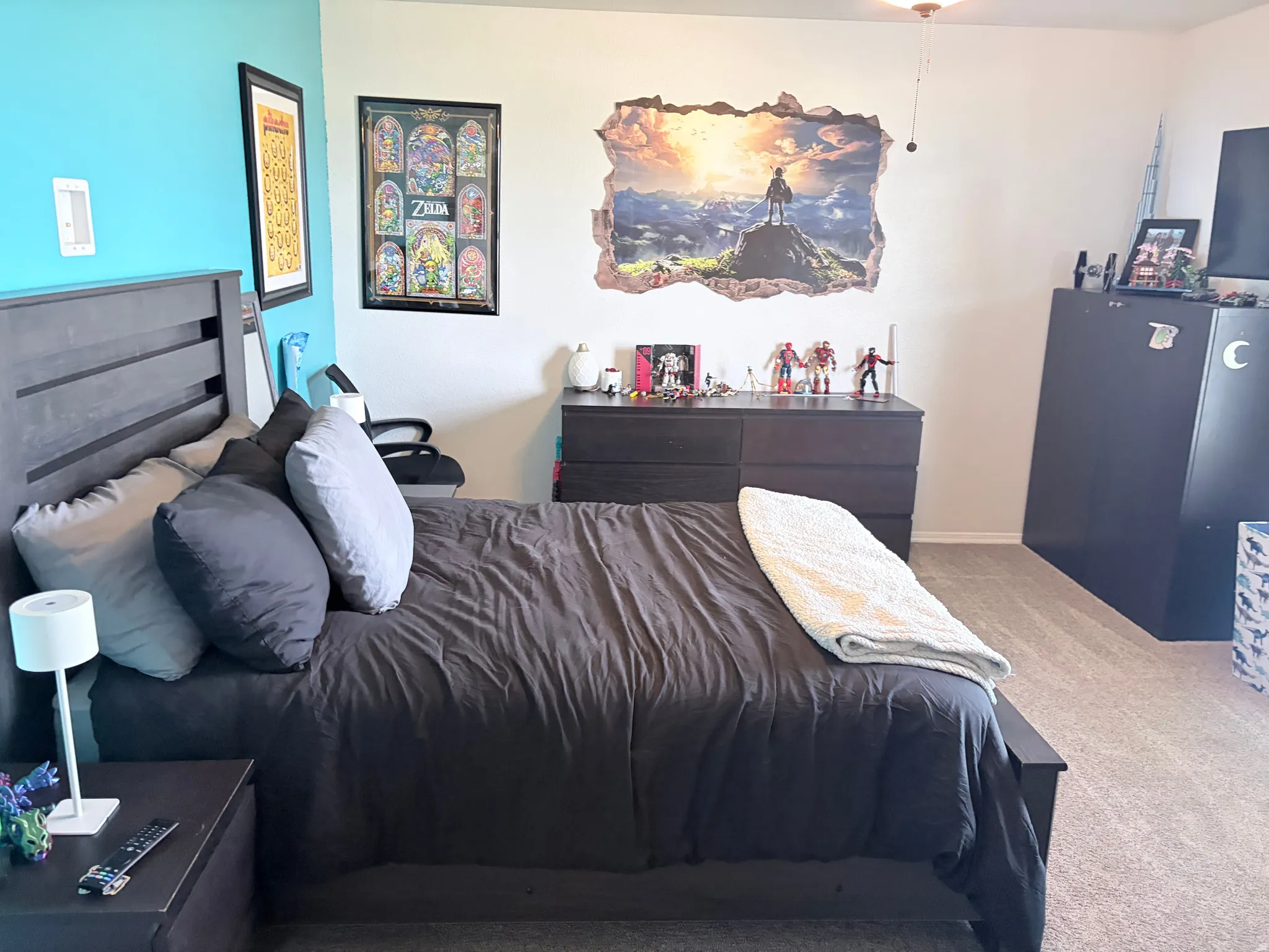 Bedroom featuring a dark wood-finish bed frame, light blue accent wall, and neutral carpeting