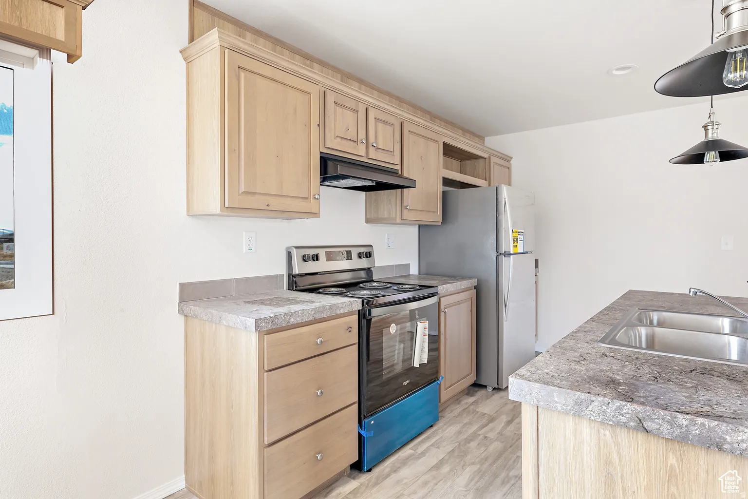 Kitchen featuring stainless steel appliances, wood-finish cabinetry, light-toned countertops, and wood-look flooring