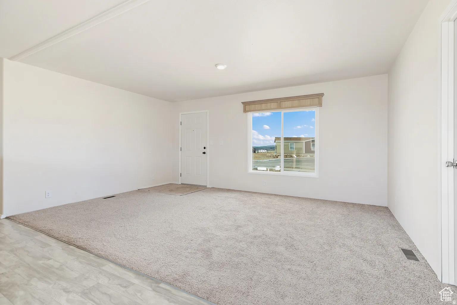 Spacious room featuring neutral carpeting and light-toned walls