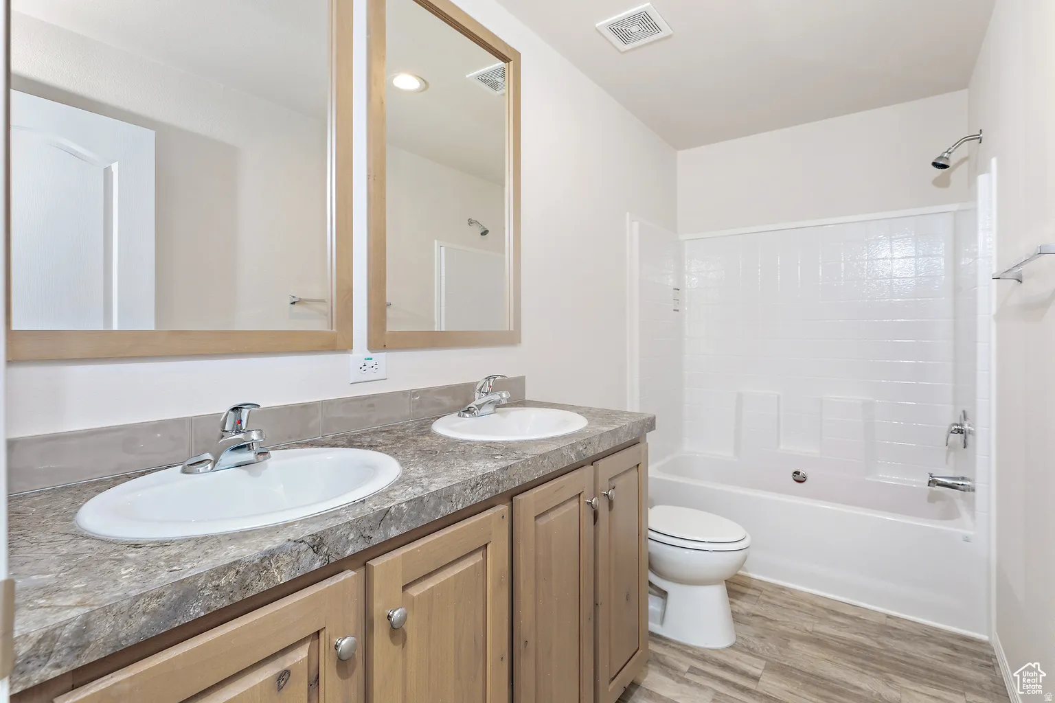 Bathroom featuring a double vanity with light wood cabinetry and dual oval sinks