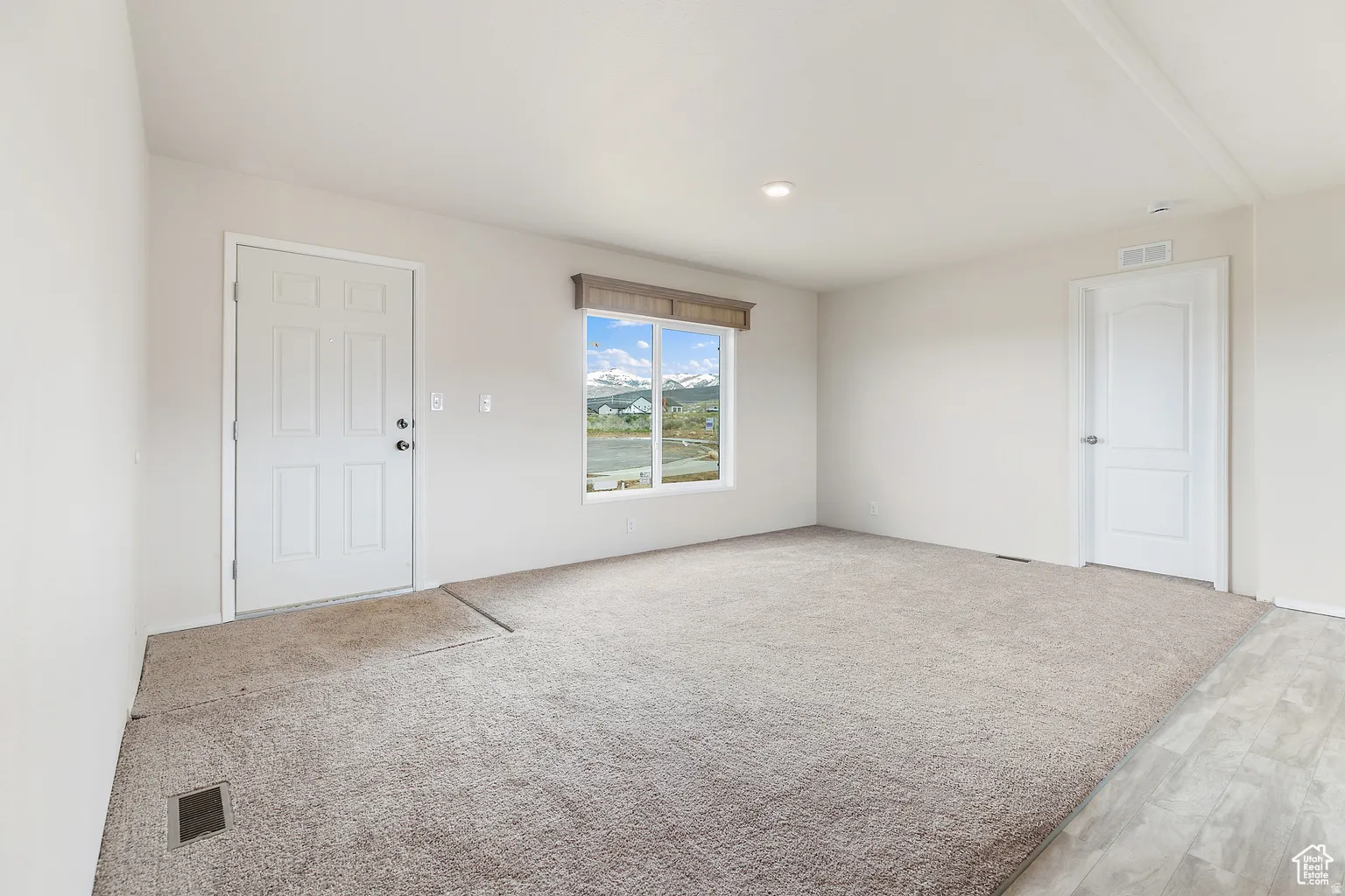 Bright interior space featuring a window with a mountain and water scenery, light-toned walls, recessed lighting, and a combination of carpet and wood-finish flooring