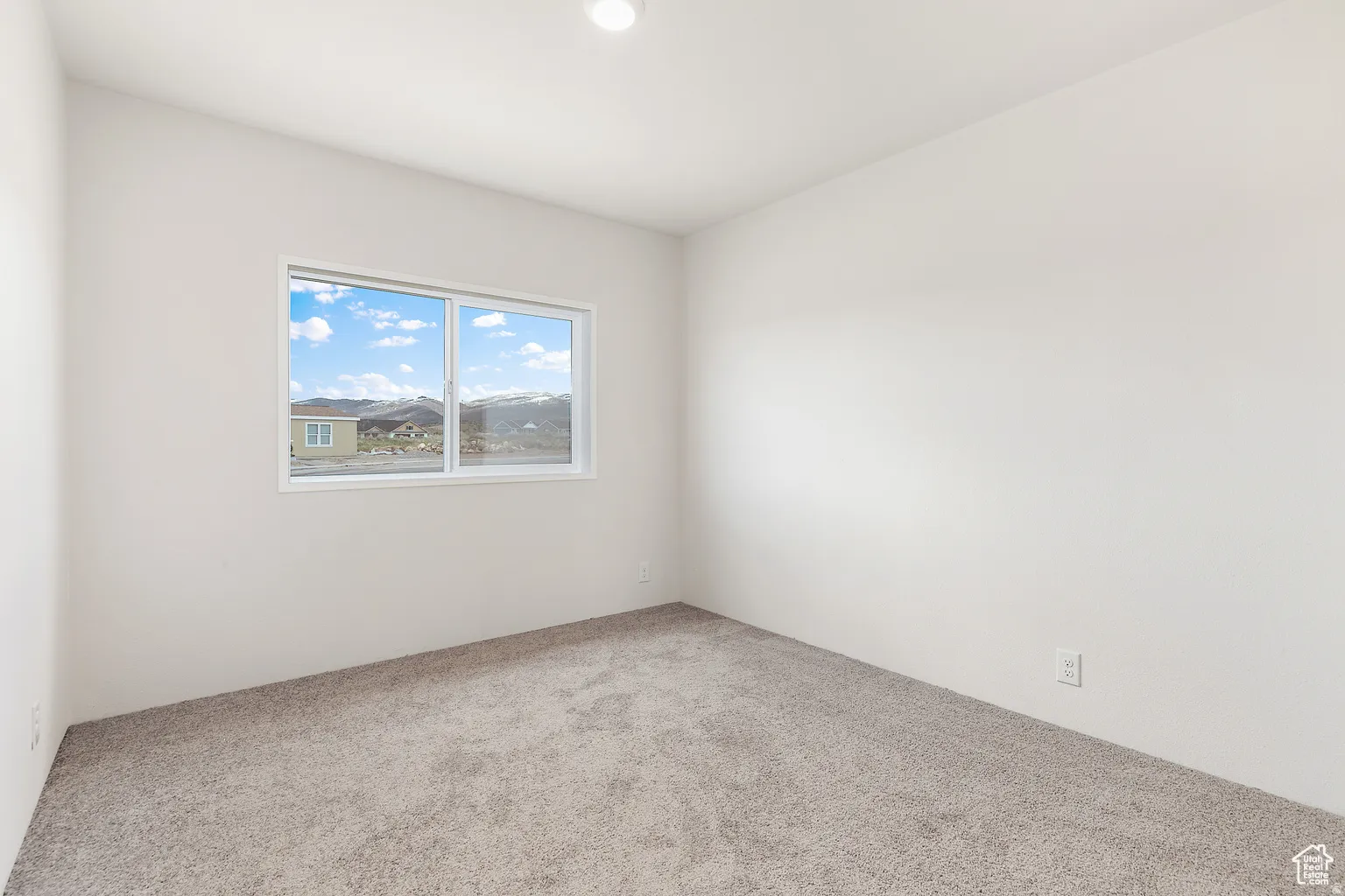 Carpeted room with white walls, featuring a window with a white frame