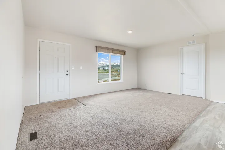 Bright interior space featuring a window with a mountain and water scenery, light-toned walls, recessed lighting, and a combination of carpet and wood-finish flooring