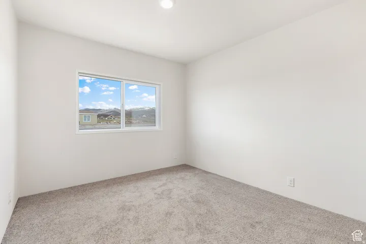 Carpeted room with white walls, featuring a window with a white frame