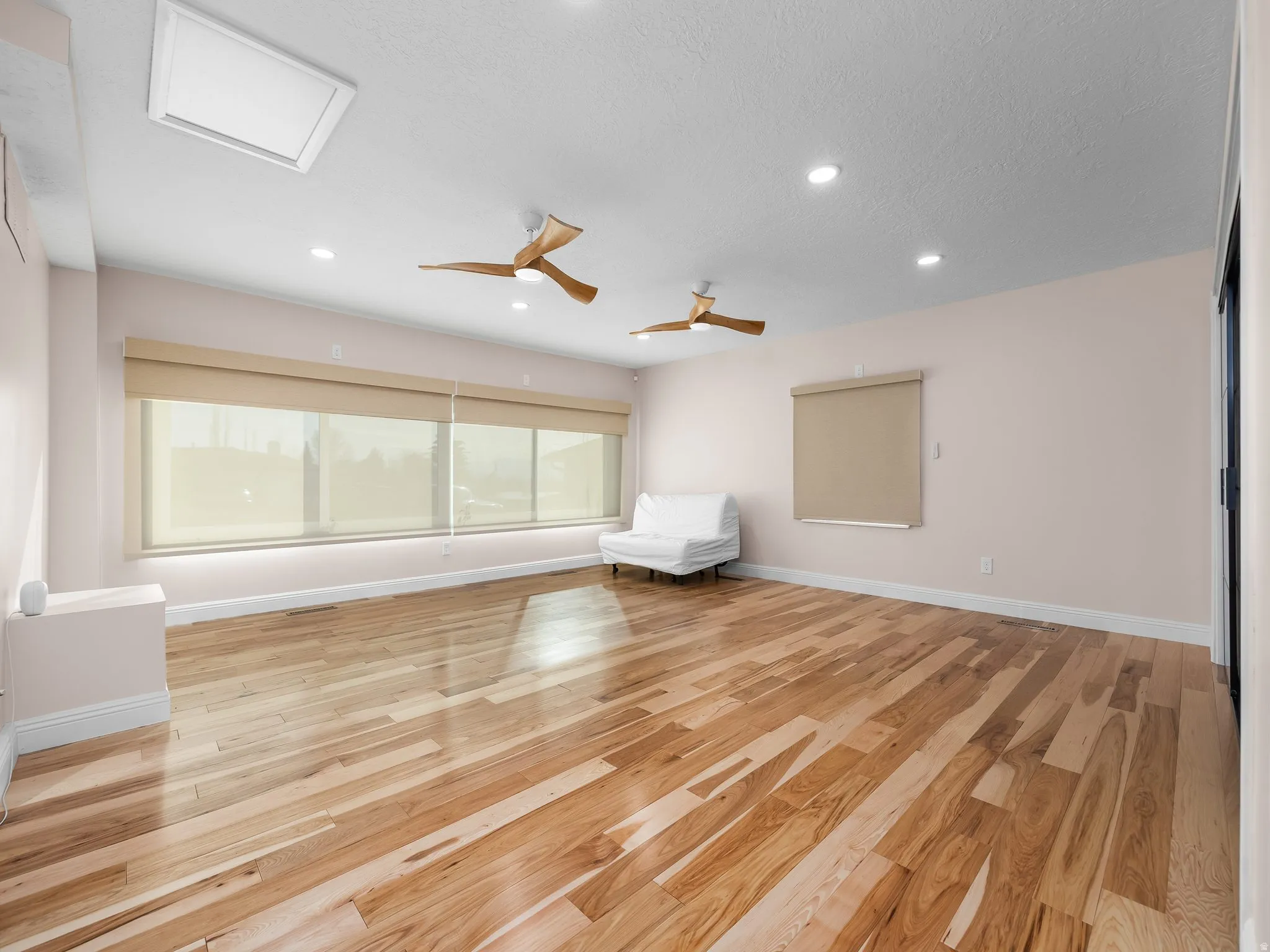Expansive interior space featuring wood-finish flooring, multiple recessed light fixtures, and a skylight