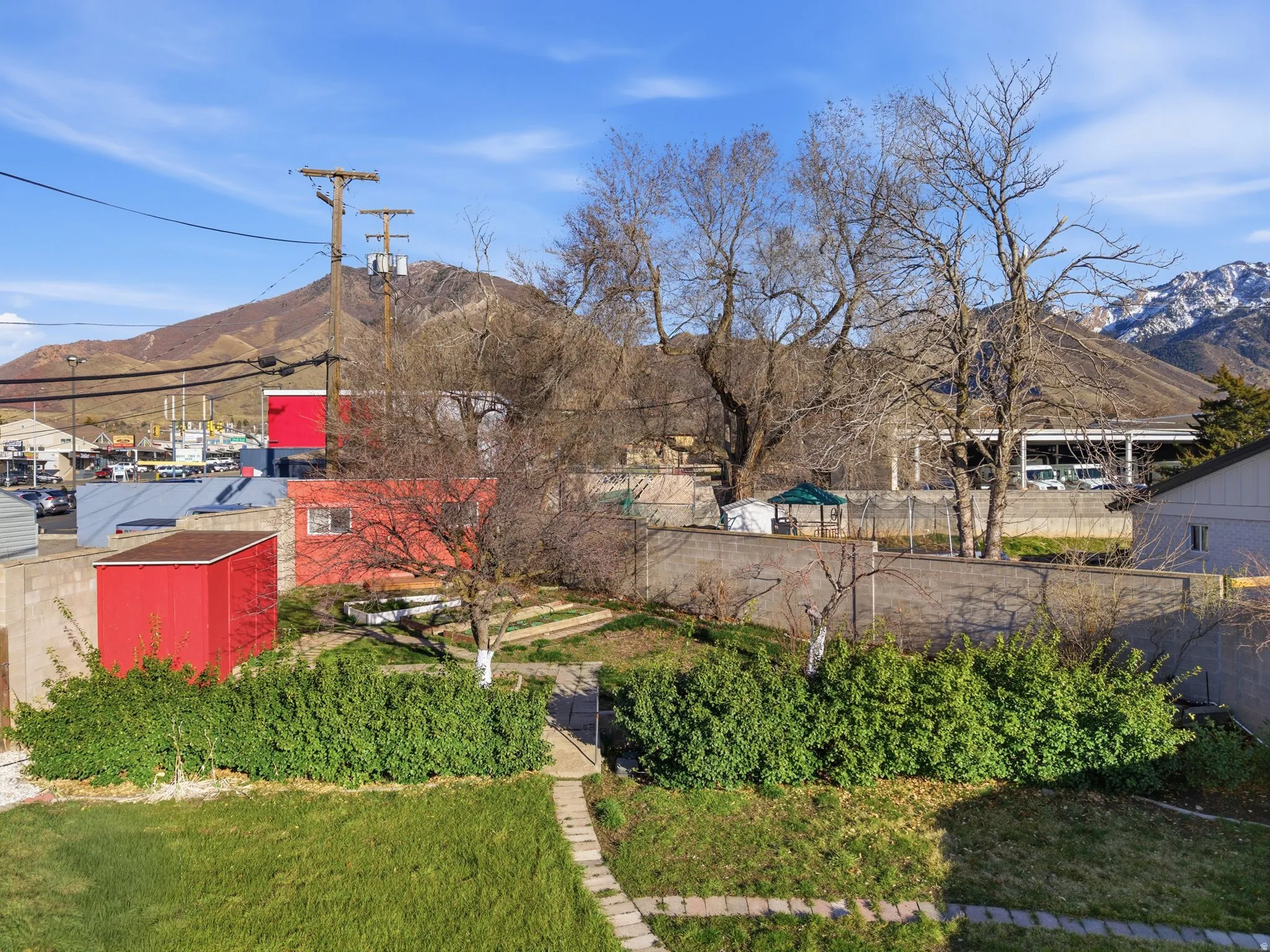 Expansive green space featuring a manicured lawn, established shrubbery, and a concrete pathway