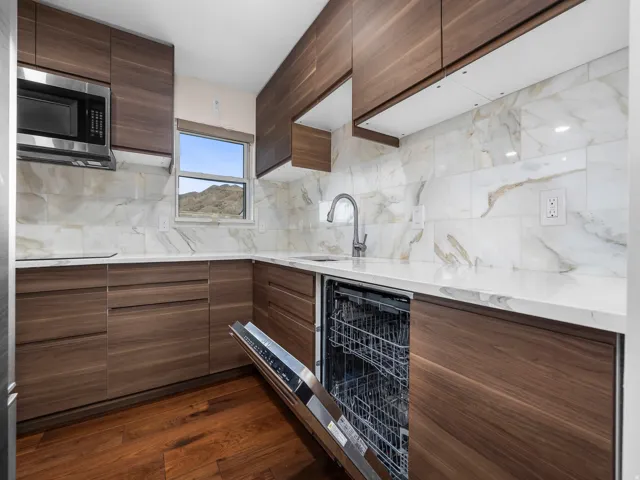 Modern kitchen featuring wood-finish cabinetry, white countertops, and a full tile backsplash