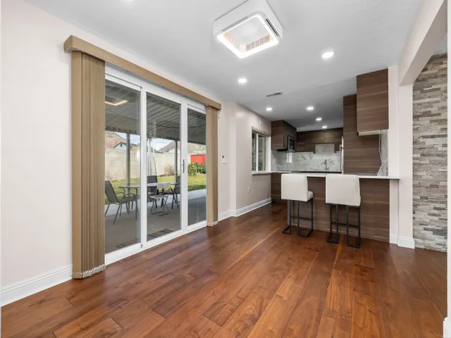 Wood-finish flooring throughout, featuring a modern kitchen with a breakfast bar, recessed lighting, and a stacked stone accent wall