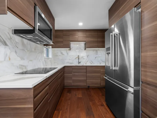 Contemporary kitchen featuring wood-finish cabinetry, white countertops, and a white marble-look backsplash