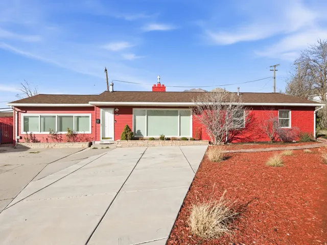 Ranch-style residence featuring a prominent red exterior, brown shingle roof, and a concrete driveway