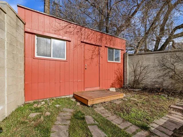 Red exterior storage shed featuring two windows, a single entry door, and a wood step
