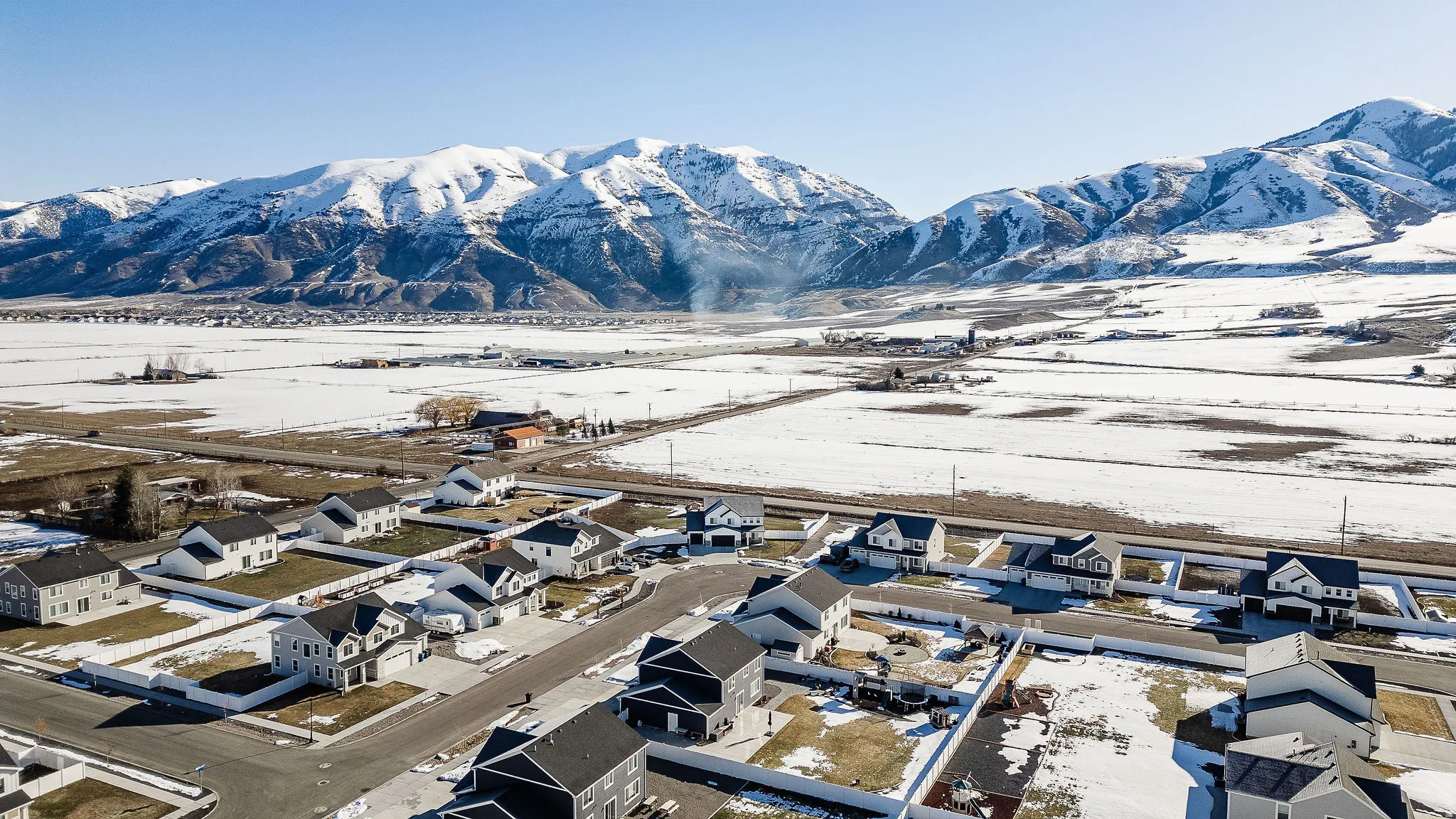 Residential community featuring detached homes with snow-capped mountains as a prominent backdrop