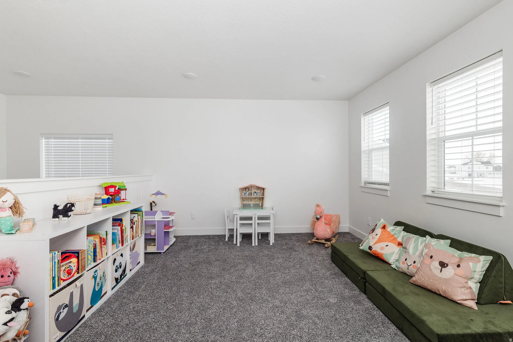 Carpeted space featuring a built-in half-wall with storage cubbies, recessed lighting, and multiple windows with blinds