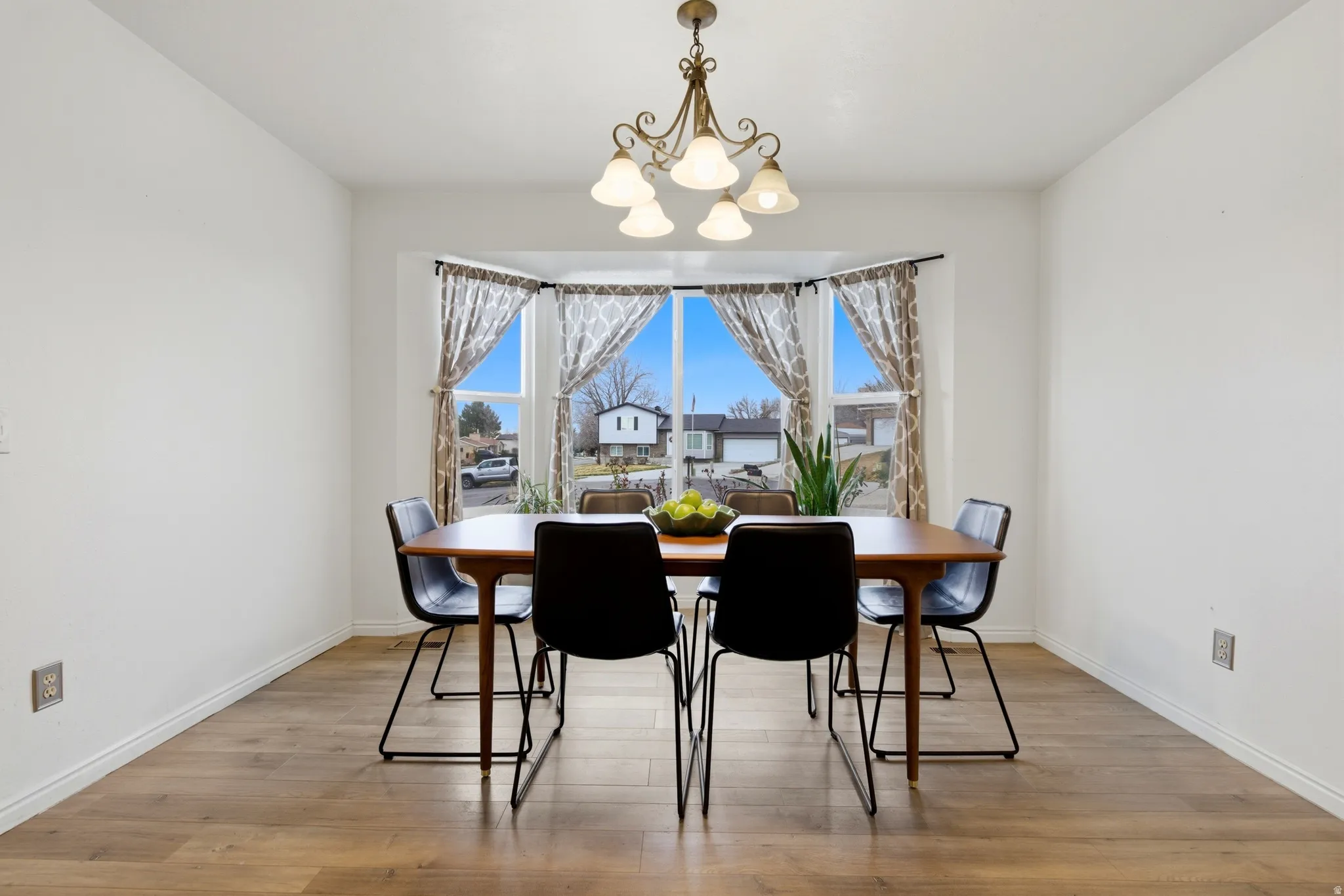 Dining area featuring a bay window, wood-finish flooring, and a decorative chandelier