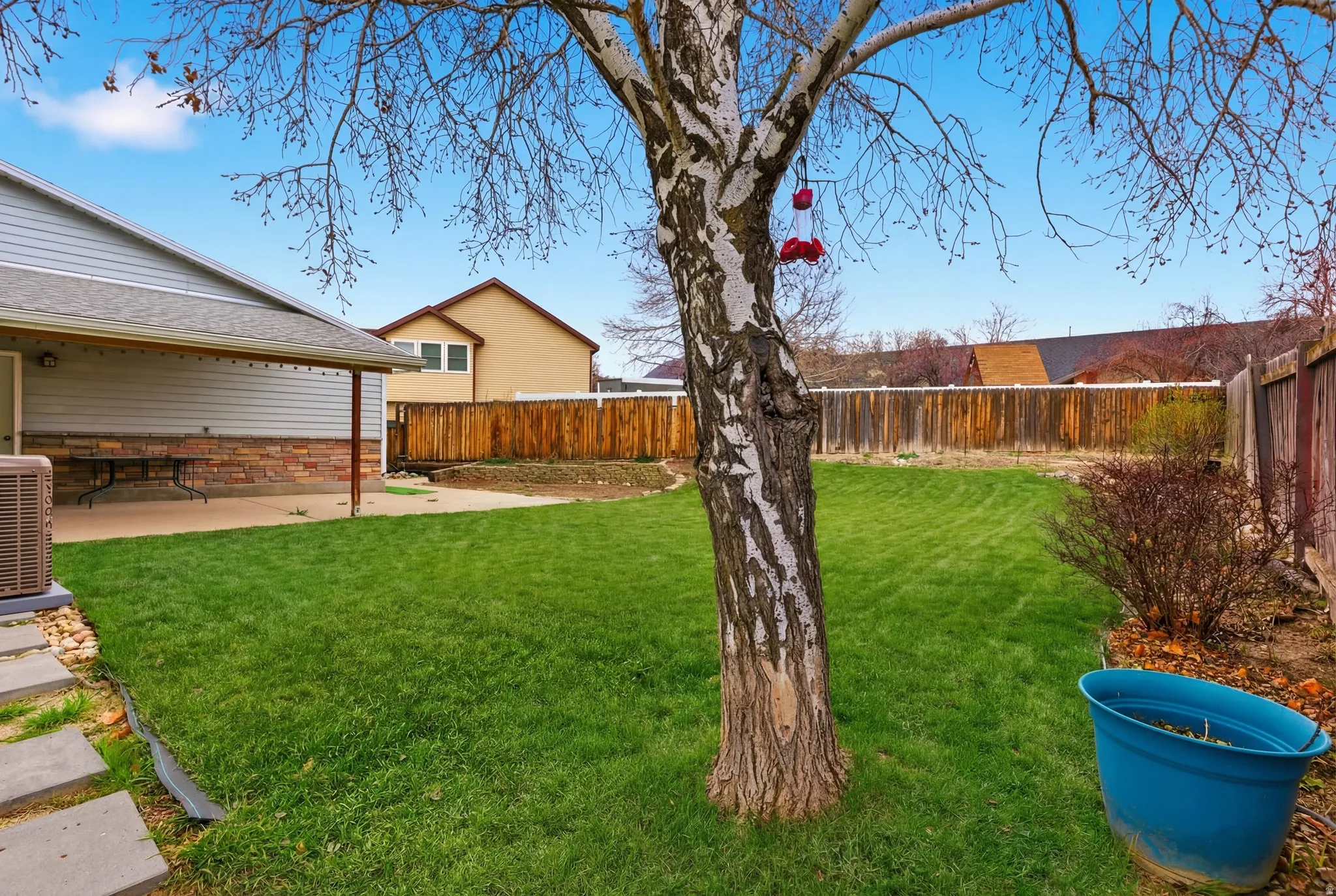 Spacious private backyard featuring a manicured lawn, established tree, and full perimeter fencing