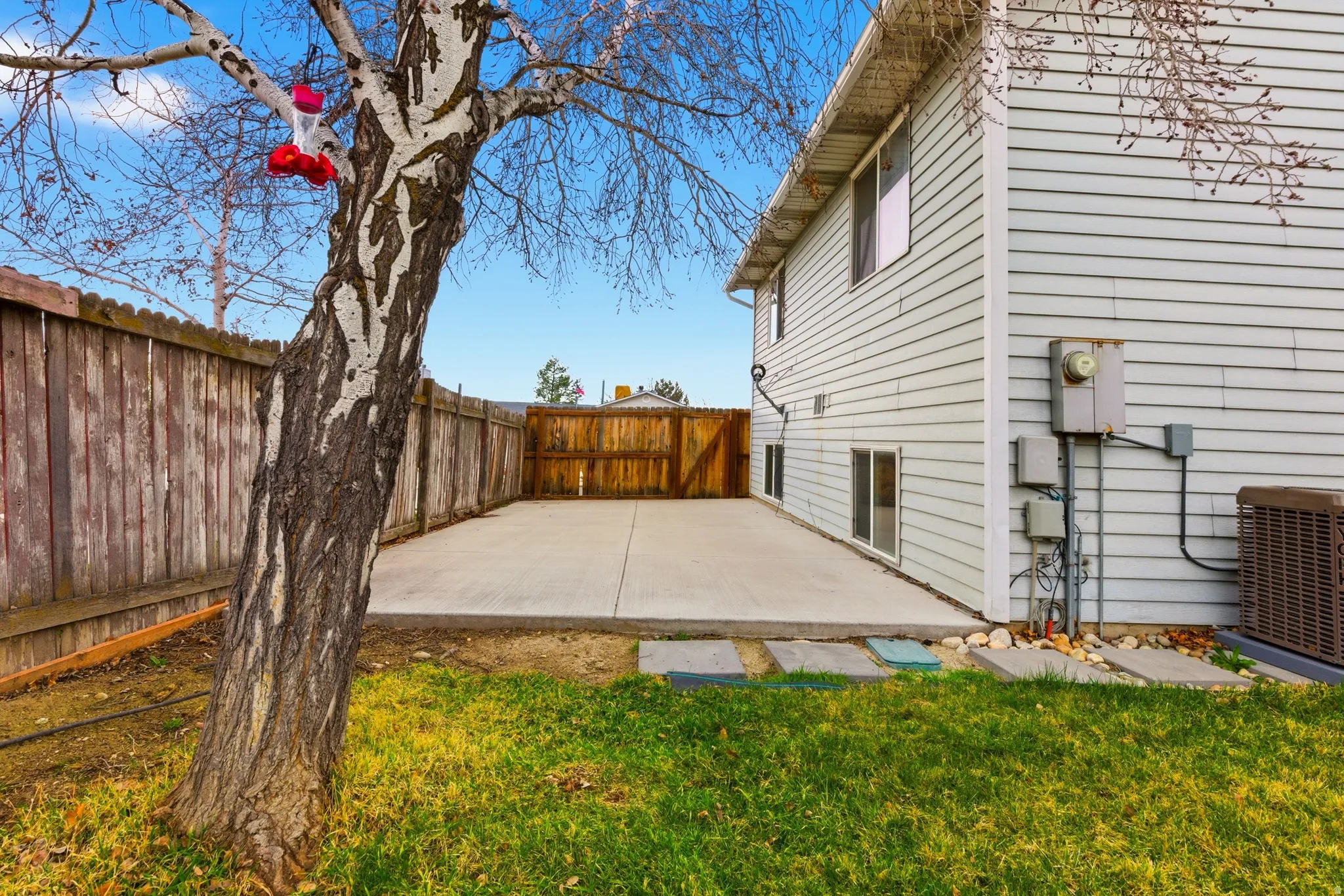 Expansive concrete patio area, bordered by wood fencing and a grassy section