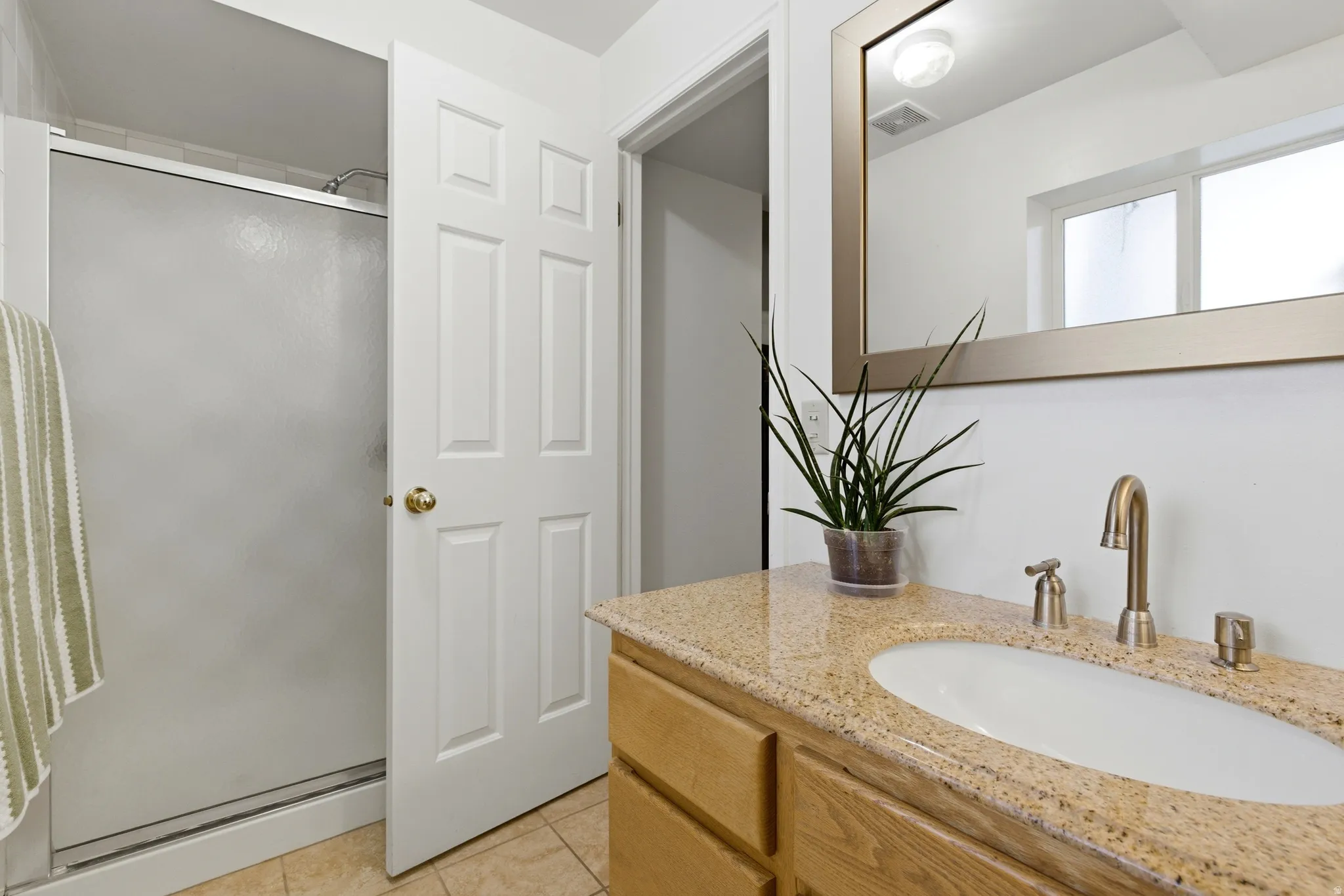 Bathroom featuring a wood-finish vanity with a granite countertop and an integrated oval sink