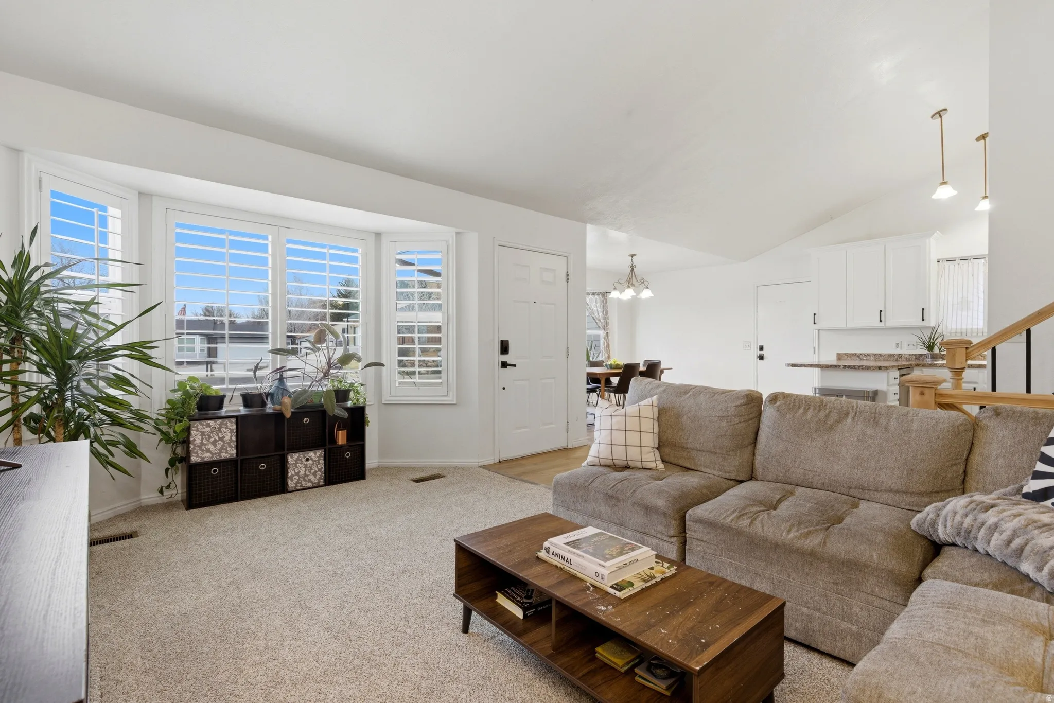 Living area featuring light-colored carpeting and a bay window with plantation shutters