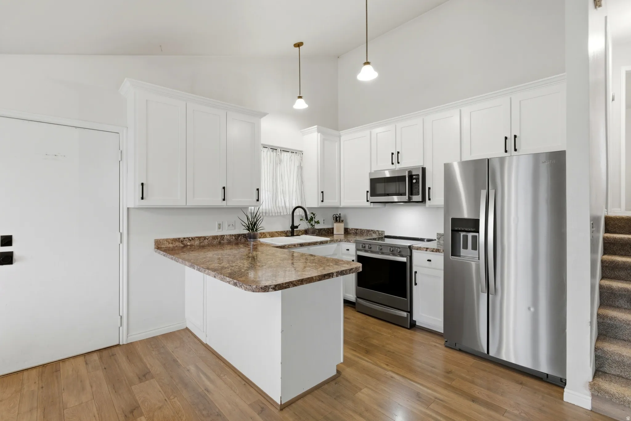 Kitchen featuring wood-finish flooring, white cabinetry with black hardware, and stone-finish countertops