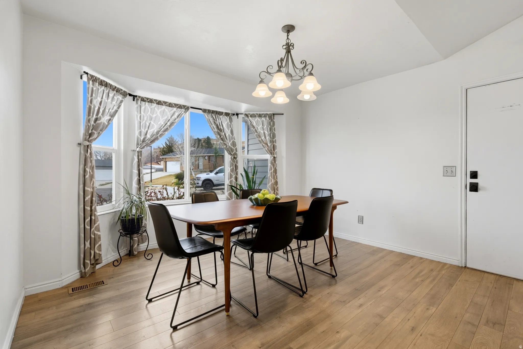 Spacious dining area featuring a bay window, wood-finish flooring, and a decorative chandelier