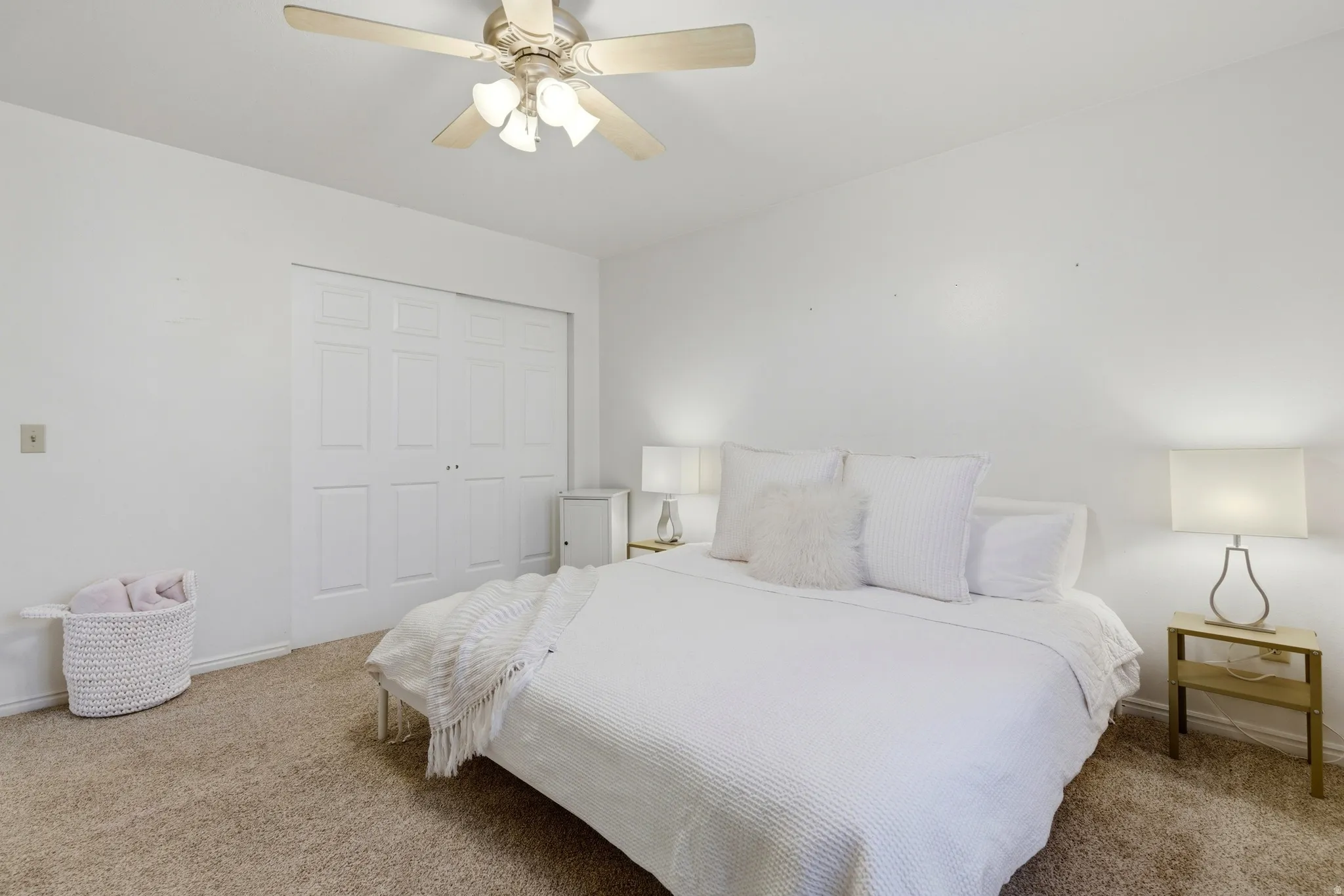 Recessed bi-fold closet doors with panel detailing, light-toned carpeting, and a ceiling fan with integrated lighting