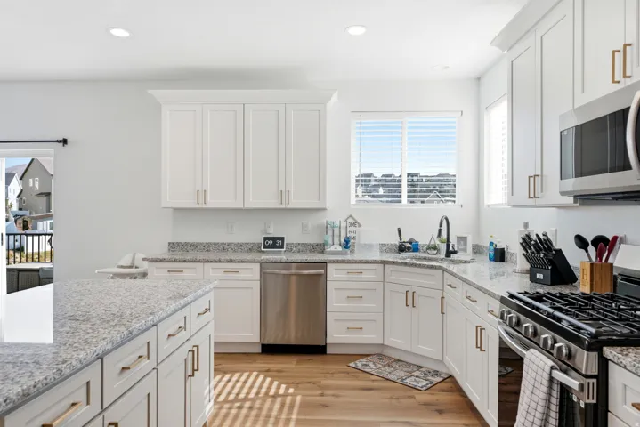Modern kitchen featuring white shaker-style cabinetry, granite countertops, and wood-finish flooring