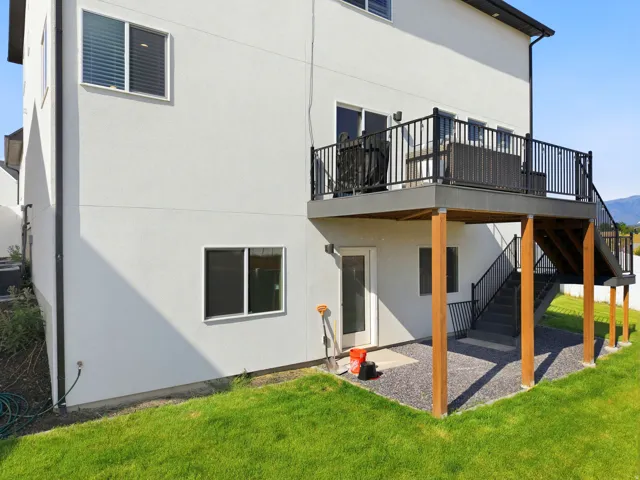 Exterior featuring a spacious upper-level deck with black railings, accessible via a sliding glass door and exterior stairs
