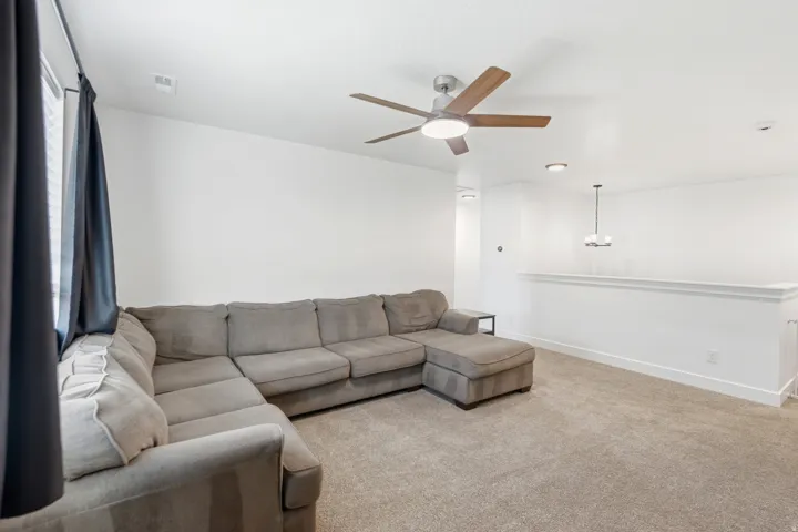 Carpeted living area featuring a ceiling fan with integrated lighting, recessed lighting, and an open railing